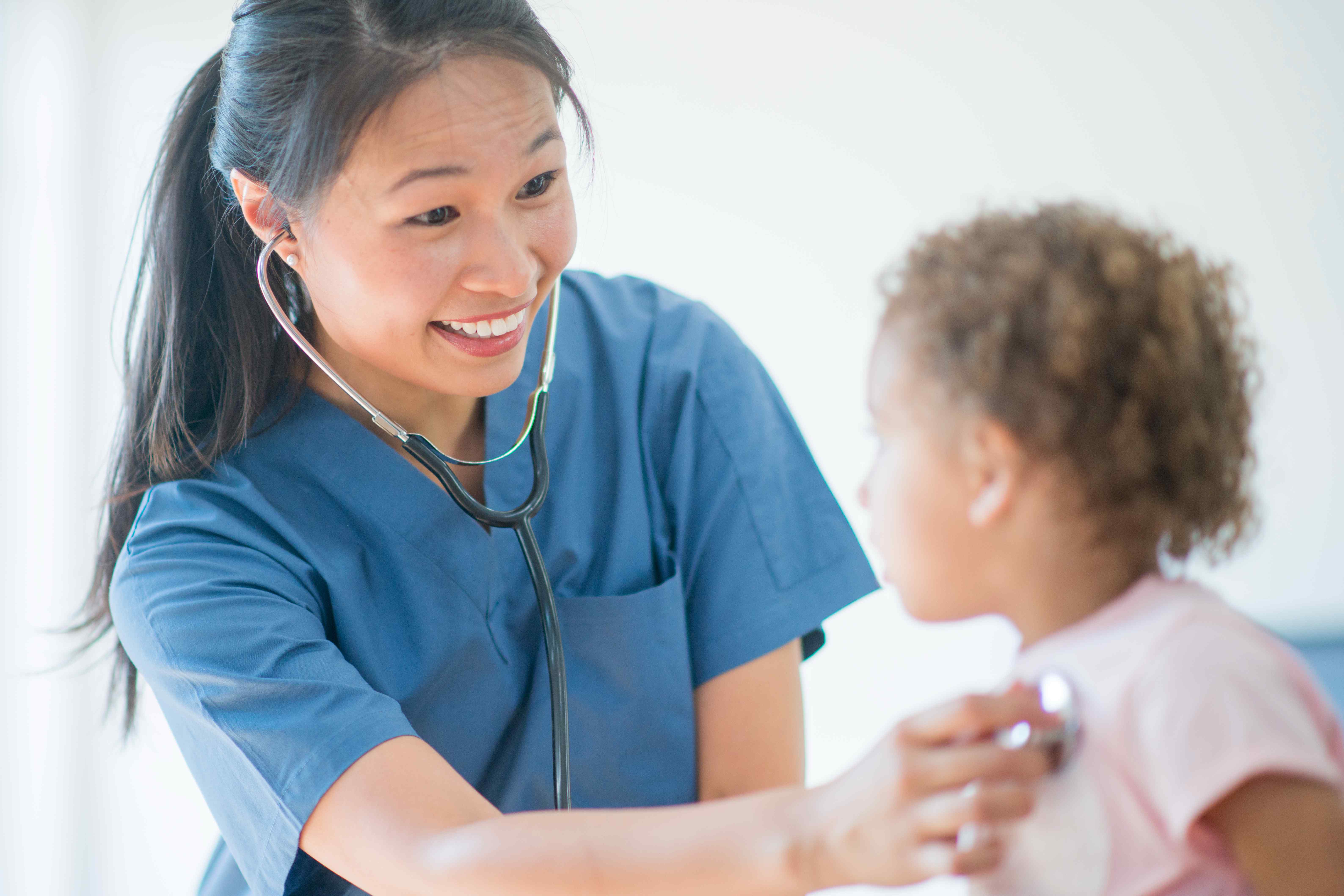 Our Story image / Female doctor smiling at a pediatric patient